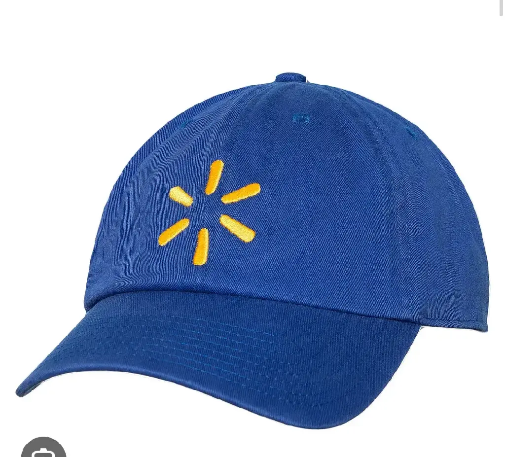 ID: A blue baseball cap with the Walmart logo, a stylized yellow asterisk, embroidered in the middle. It is part of the employee uniform